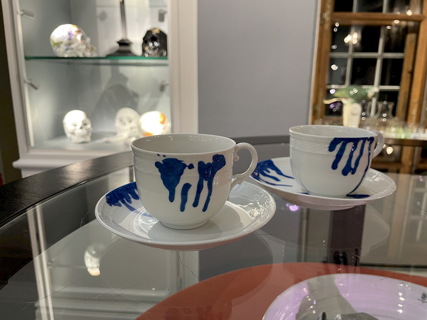 Zwei weiße Kaffeetassen mit Untertassen und blauer Bemalung in der Art von tropfenden Farbspuren aus der Serie Generation T dripping.