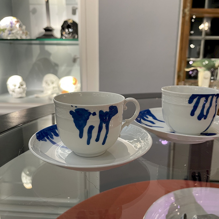 Zwei weiße Kaffeetassen mit Untertassen und blauer Bemalung in der Art von tropfenden Farbspuren aus der Serie Generation T dripping. © Claudia Dobner