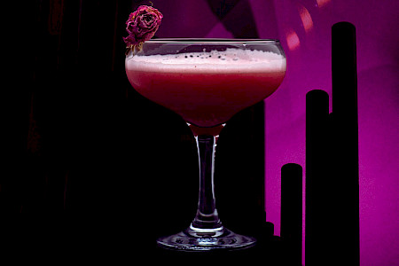 Cocktailglas vor Orgelpfeifen in violetter lounge-artiger Hintergrundbeleuchtung