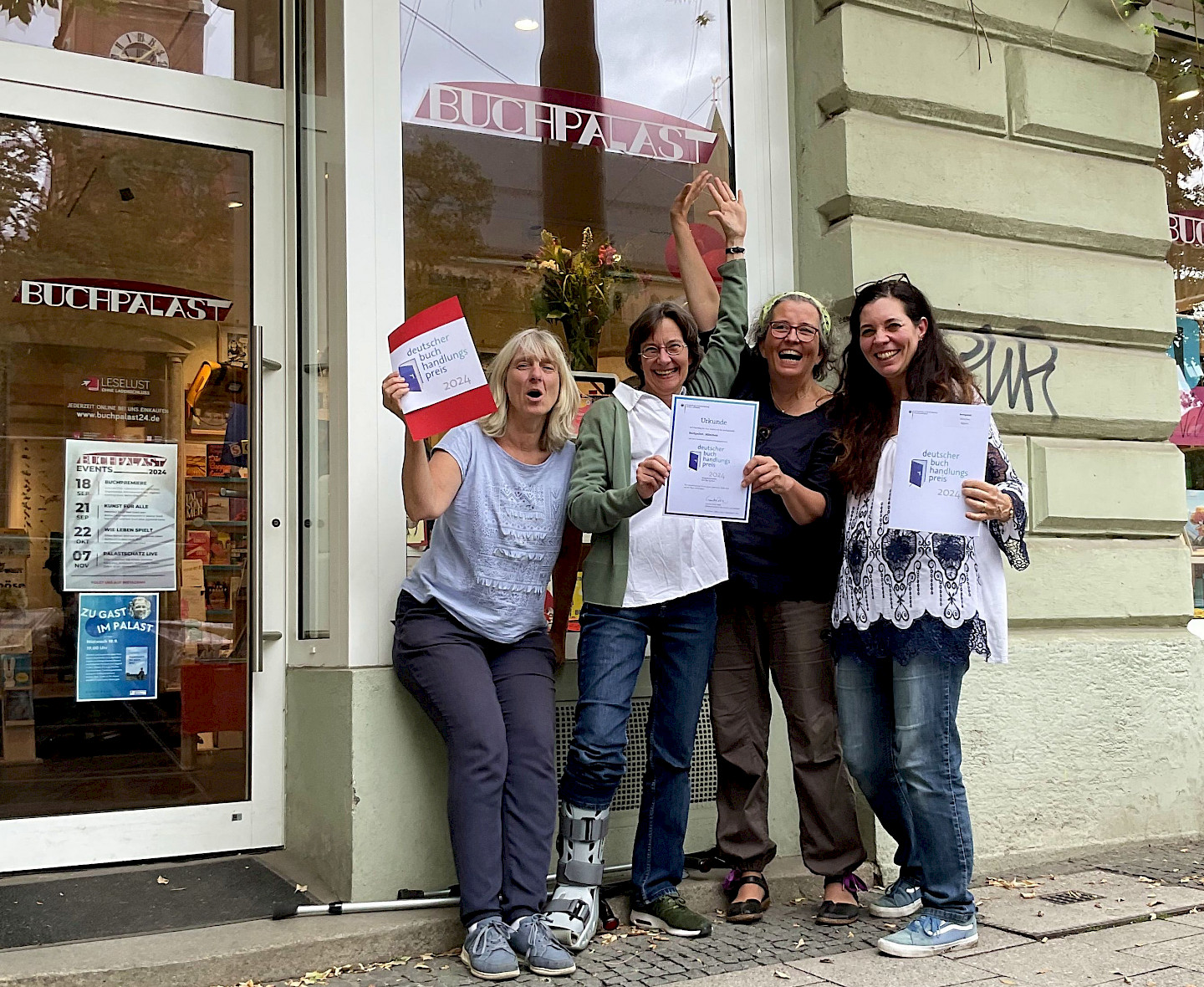 Das Team des Buchpalastes, vier Frauen mit der Urkunde des Deutschen Buchhandlungspreises in der Hand, stehen vor ihrem Ladengeschäft.