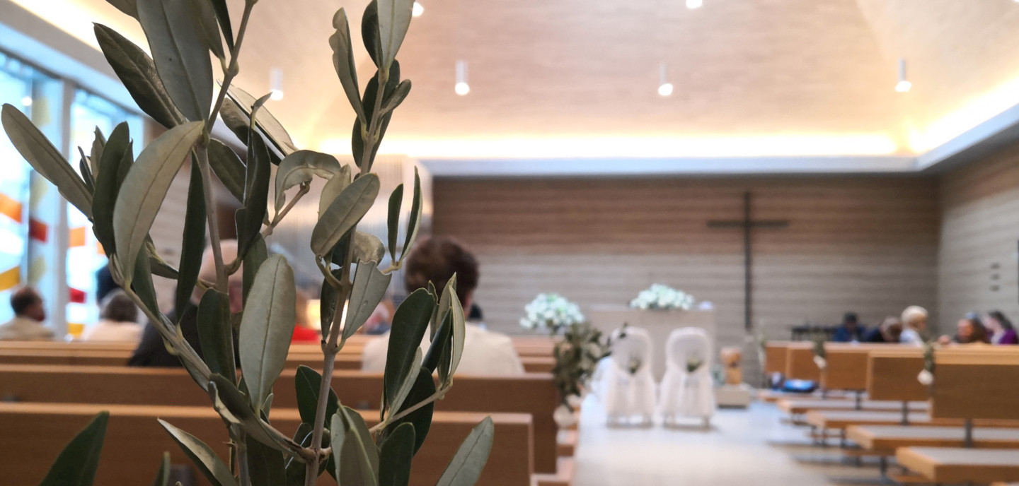 Innenansicht der Neuapostolischen Kirche München Mittersendling Ansicht durch die Bankreihen der Kirche auf Altar und Kreuz