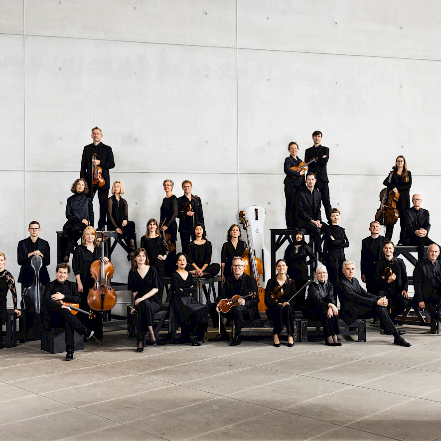 Die Musiker und Musikerinnen stehen als Gruppe mit ihren Instrumenten vor der Kamera © Daniel Delang